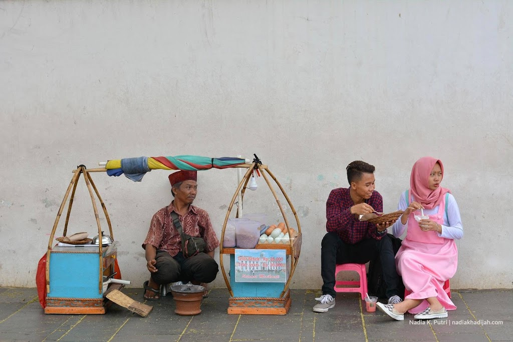 Pengunjung menikmati kerak telor di kawasan objek wisata Kota Tua, Jakarta. Susah senang bersama pasangan, makan kerak telor dulu supaya santai. (Foto: Nadia K. Putri)